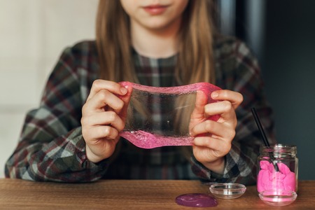 The child is holding a toy called mucus, the child is having fun and experimenting.
