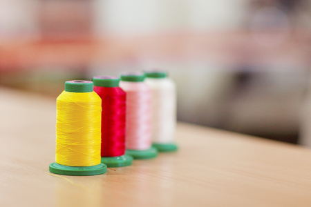 Sewing accessories on a wooden table. Sewing thread close-up yellow and red.