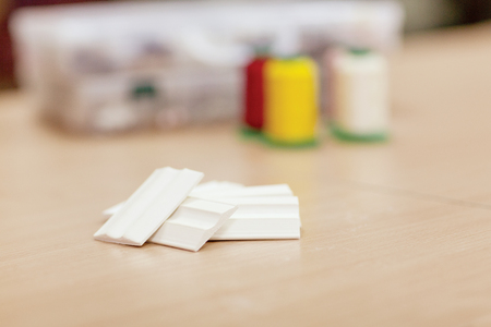 Sewing accessories on a wooden table close-up. Sewing thread and chalk for cutting