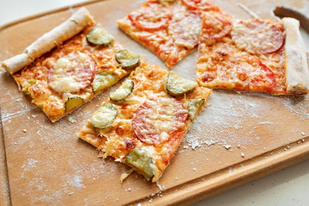 Pizza with mozzarella cheese, salami, tomatoes and spices. Italian pizza on a wooden board. Close-upの写真素材