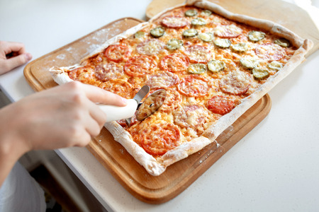 child cuts pizza with a roller cutter close up