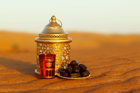 Lantern, cup and dates in the desert at a beautiful sunset, symbolizing Ramadan