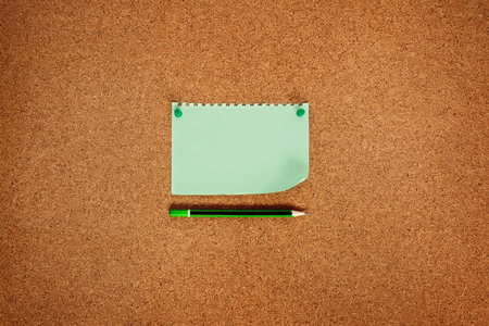 Note paper with green buttons and a cork board pencil, top view