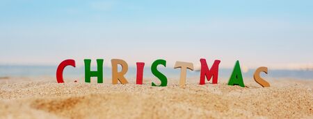 Christmas lettering in colored letters on the beach on a background of the sea. Panoramic photo. Christmas and New Year holidays in the concept of warm countries.の写真素材