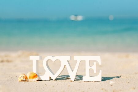 Wooden letters love on a sandy beach overlooking the blue seaの写真素材