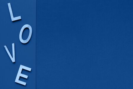 The word love consists of wooden letters located on a blue background with space for text. Postcard to Valentine's Day and Women's Day.の写真素材