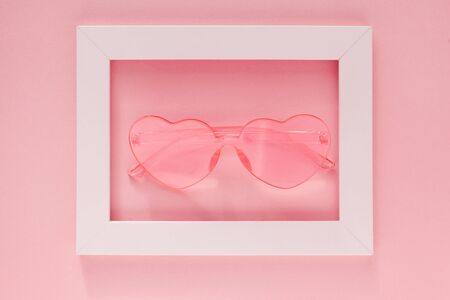 Pink heart-shaped glasses in a white frame on a pink background. Postcard, gift, greeting for...