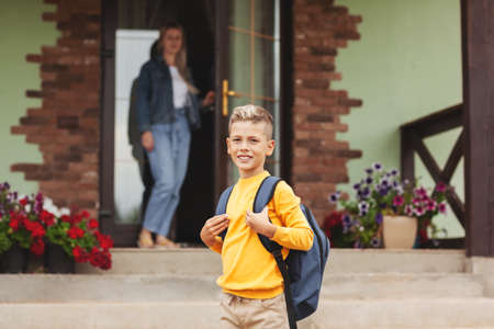 Mom, standing at the door near her house, escorts her son to school, back to school.の写真素材