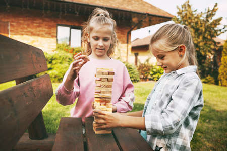 Two girls play a wooden board game outdoors near their house.の写真素材