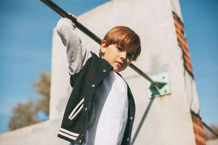 Cute boy holds on to the horizontal bar and looks at the camera