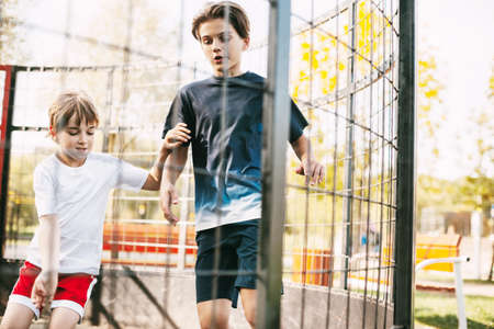 Two cute teenagers play soccer on the freestyle soccer field. Boys fight for the ball in the game....