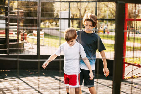 Two cute teenagers play soccer on the freestyle soccer field. Boys fight for the ball in the game....