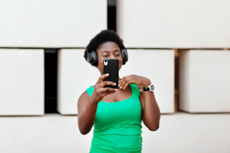 Close - up of the phone in the hands of an African girl who listens to music in wireless headphones...