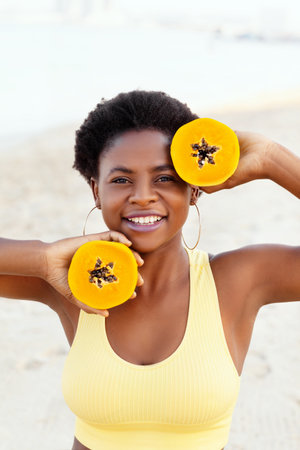 Portrait of a charming African girl with a papaya in her hands on the beachの写真素材