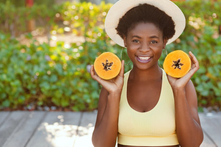 Portrait of a charming African girl in a straw hat with a papaya in her hands