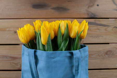 Bouquet of yellow tulips on a wooden background with place for text. View from above. Valentines...
