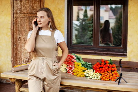 Portrait of a young female florist standing next to a table with tulips on it. Womens Day and Valentines Day, Mothers Dayの写真素材