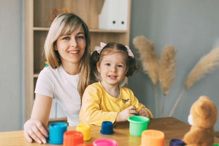Portrait of a young mother and her little daughter playing at a table with colorful molds. Time together, motherhood, parenthoodの写真素材