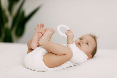 The kid lies in a snow-white bed under the covers, laughs and indulgesの写真素材