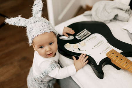 Father sits in the room in an armchair and plays the guitar to his babyの写真素材