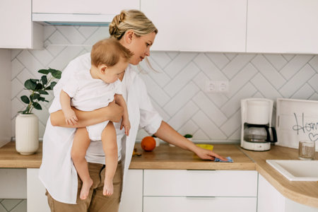 A young mother with a small boy cleans the kitchen at home, Household chores on maternity leaveの写真素材