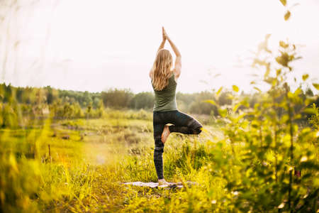 A young woman performs a yoga asana outdoors. Rear view, space for text. Yoga, fitness, sportsの写真素材