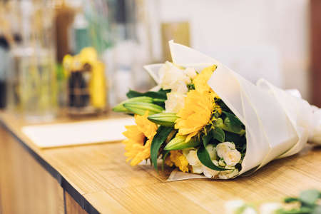 A beautiful bouquet of bright mixed flowers lies on a wooden table, the work of a florist in a flower shopの写真素材