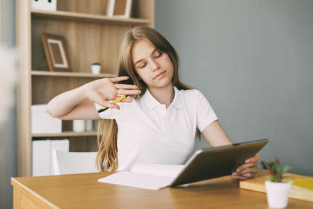 A teenage girl does her homework with her friends via video link using a tablet