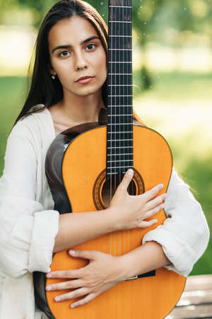 Portrait of a beautiful musician girl with a guitar in the park. Girl-musician, music, hobby....