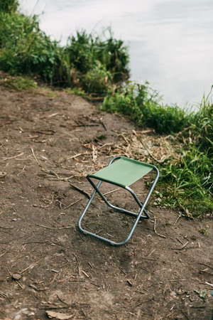 An empty chair for relaxing or fishing stands on the bank of a river or lakeの写真素材