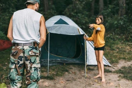 A happy father and daughter are setting up a camping tent. Family time, family rest, careの写真素材