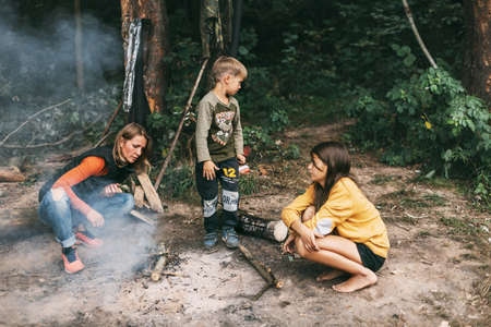 A happy family makes a fire during a trip in the forest. Spending time together, family timeの写真素材