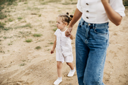Mom and her little daughter are walking, holding hands, spending time together
