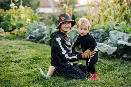 A happy blond boy and his sister in carnival skeleton costumes are playing in the garden on Halloween eveの写真素材