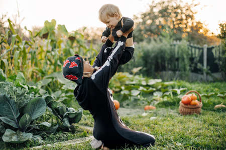 The older sister and her little brother in skeleton costumes, the girl throws the boy up. Halloween eve, holiday, traditionsの写真素材