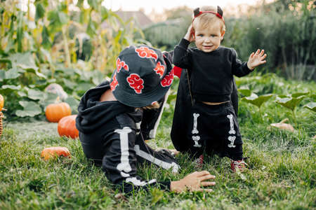 Holiday and Childhood concept - Happy children in Halloween costumes play in the garden on Halloween eveの写真素材