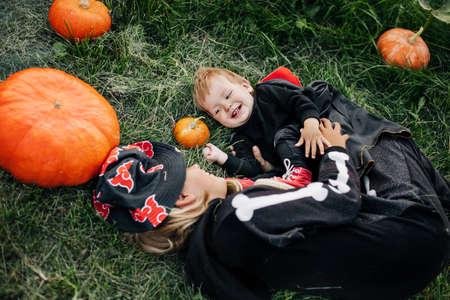 A little boy and his sister play on the grass in the garden on Halloween eve. The concept of a holiday, traditions and childhoodの写真素材