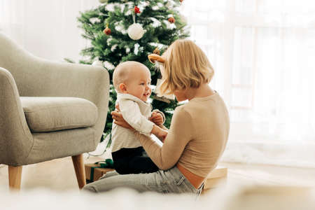 Brother and sister play together in a chair next to the Christmas tree. Kids have fun together. The concept of Christmas and New Yearの写真素材
