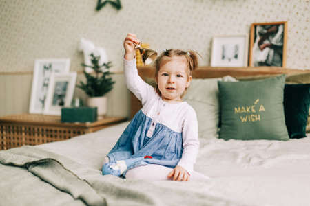 A happy girl is playing on the bed on Christmas morning in a room decorated for Christmas or New Year. Childhood, festive morning, Christmas moodの写真素材