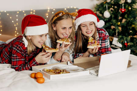 A young mother and her two wonderful daughters enjoy a pizza delivered and a movie in the evening,...