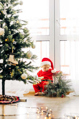 Cute baby under the tree in a New Years costume on Christmas Eve or New Years Eveの写真素材