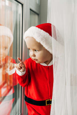 A kid in a New Years costume is waiting at the Christmas window. Christmas, waiting for the holiday, magicの写真素材