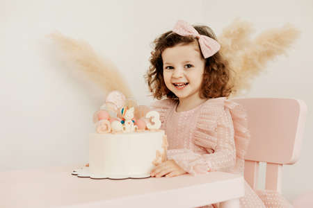 Portrait of a charming little girl with a cake during a birthday celebrationの写真素材
