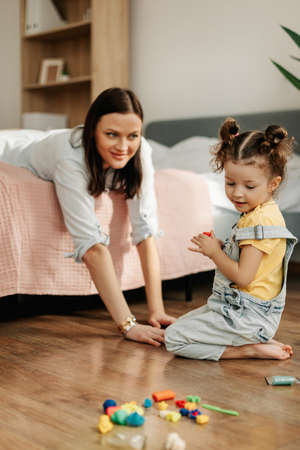 Mom and little daughter at home sculpt from plasticine and play together. The concept of preschool or home educationの写真素材