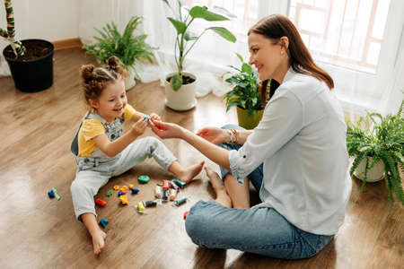 Mom and little daughter at home sculpt from plasticine and play together. The concept of preschool or home educationの写真素材