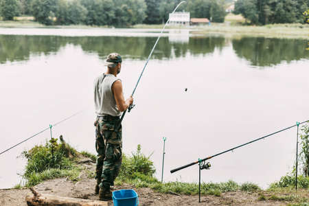 A young fisherman catches fish on a lake or river, prepares tackle and bait. Hobbies, weekends, fishingの写真素材