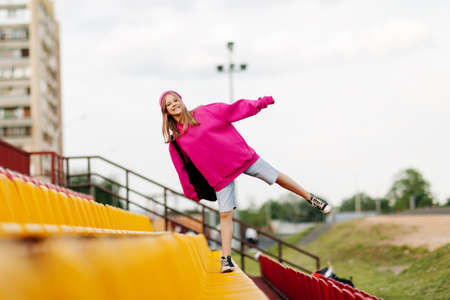 A teenage girl with a backpack walks through the stands of the school stadiumの写真素材