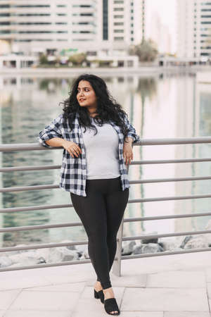 A charming Indian woman laughs while walking around the city. The concept of urban life.