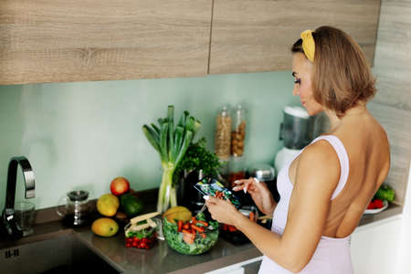 A female food photographer with a mobile phone takes pictures of a vegetable salad for her blog about healthy eating and a healthy lifestyle.の写真素材