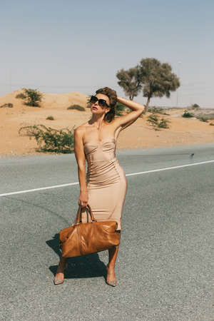 An elegant woman poses on a deserted road. Fashion, glamour, style.の写真素材
